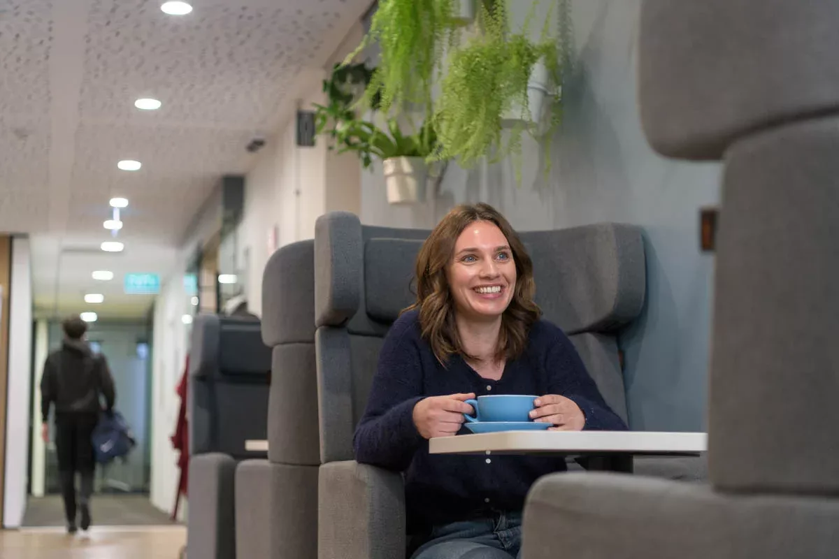 Smiling woman drinks coffee in Urban Hub's coffee area