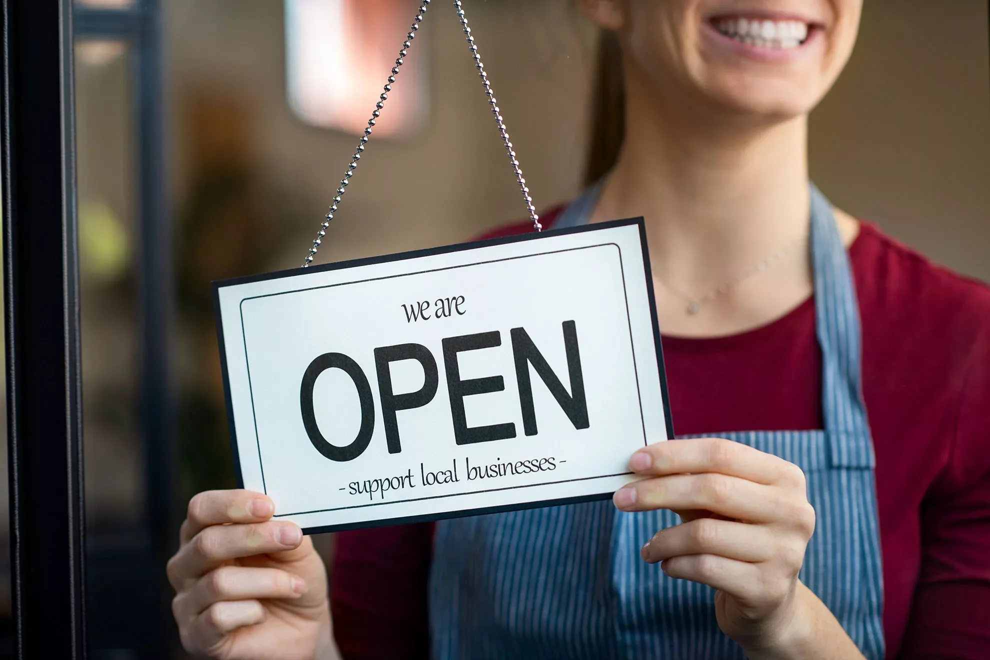 Smiling woman changes business sign to 'open'