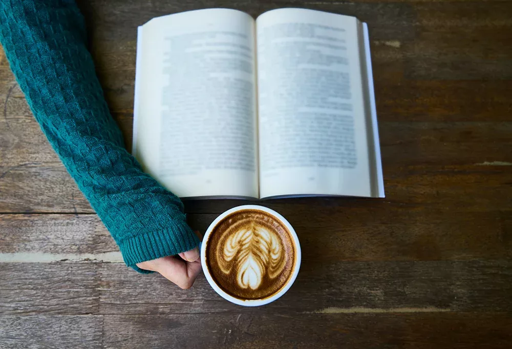 Person reading book with coffee